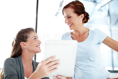 Buy stock photo A young businesswoman showing her colleague something on a digital tablet
