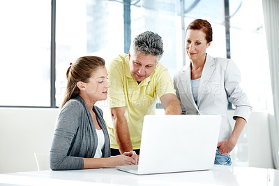 Buy stock photo A group of professionals working together as a team at a laptop