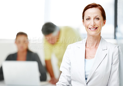 Buy stock photo Portrait of a mature businesswoman standing confidently with her colleagues in the background