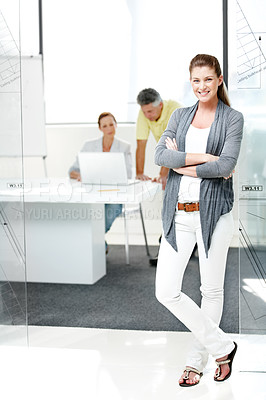 Buy stock photo Full-length shot of a young female architect standing confidently with her colleagues in the background
