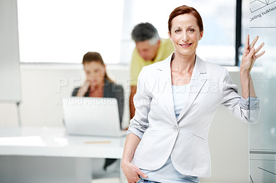 Buy stock photo A mature female architect standing confidently with her colleagues in the background