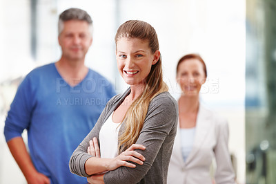 Buy stock photo An attractive young businesswoman standing confidently with her co-workers in the background