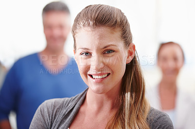 Buy stock photo Closeup of an attractive young businesswoman standing confidently with her co-workers in the background