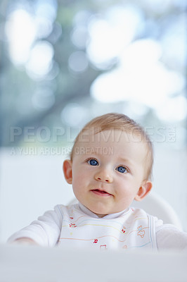 Buy stock photo A baby boy looking up at something while sitting in his high chair