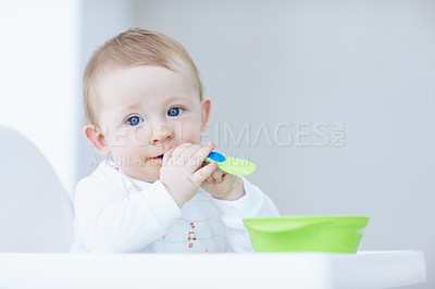 Buy stock photo A cute baby boy in his high chair holding a plastic spoon