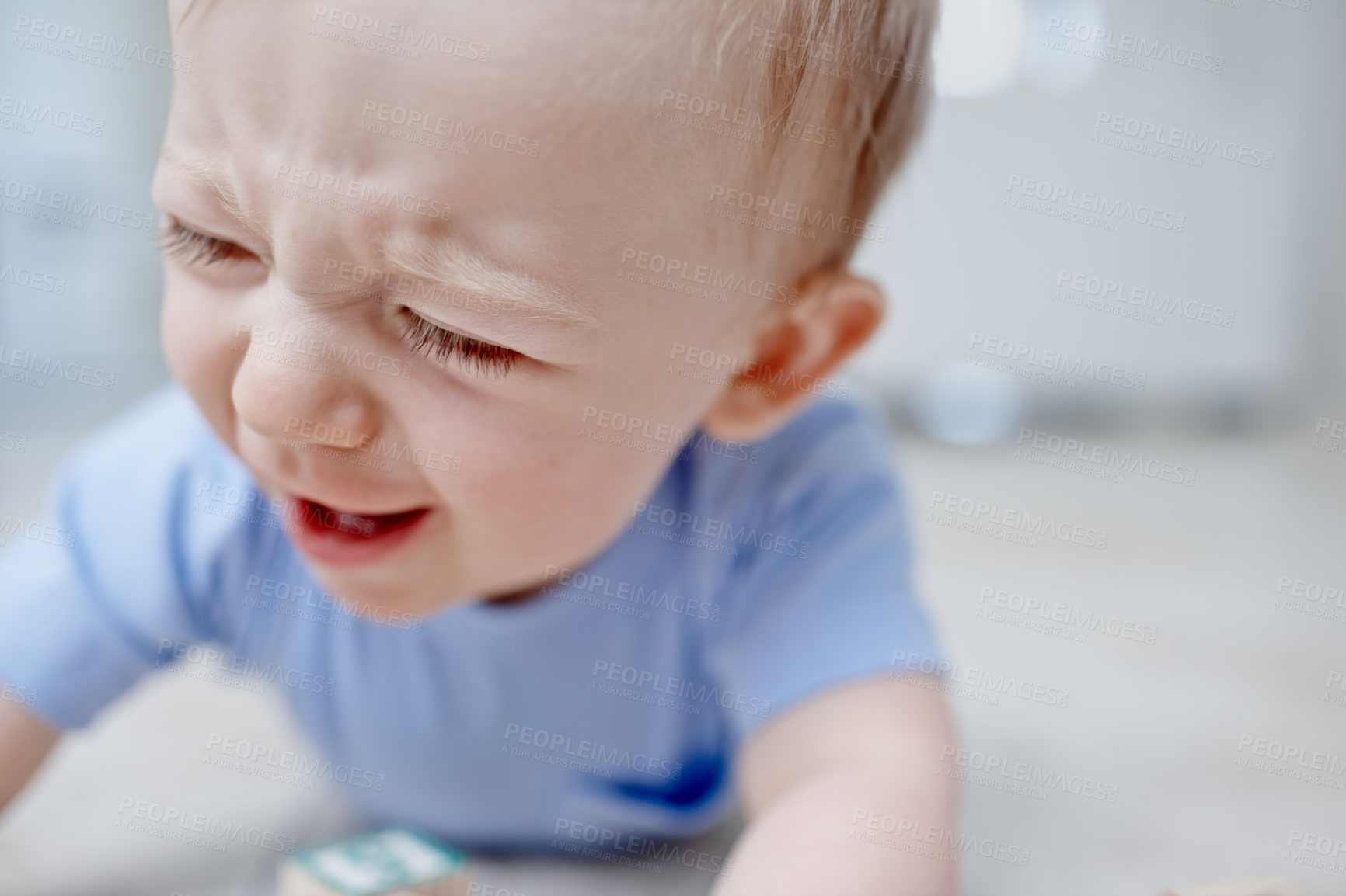 Buy stock photo Closeup of a crying baby boy lying on the floor