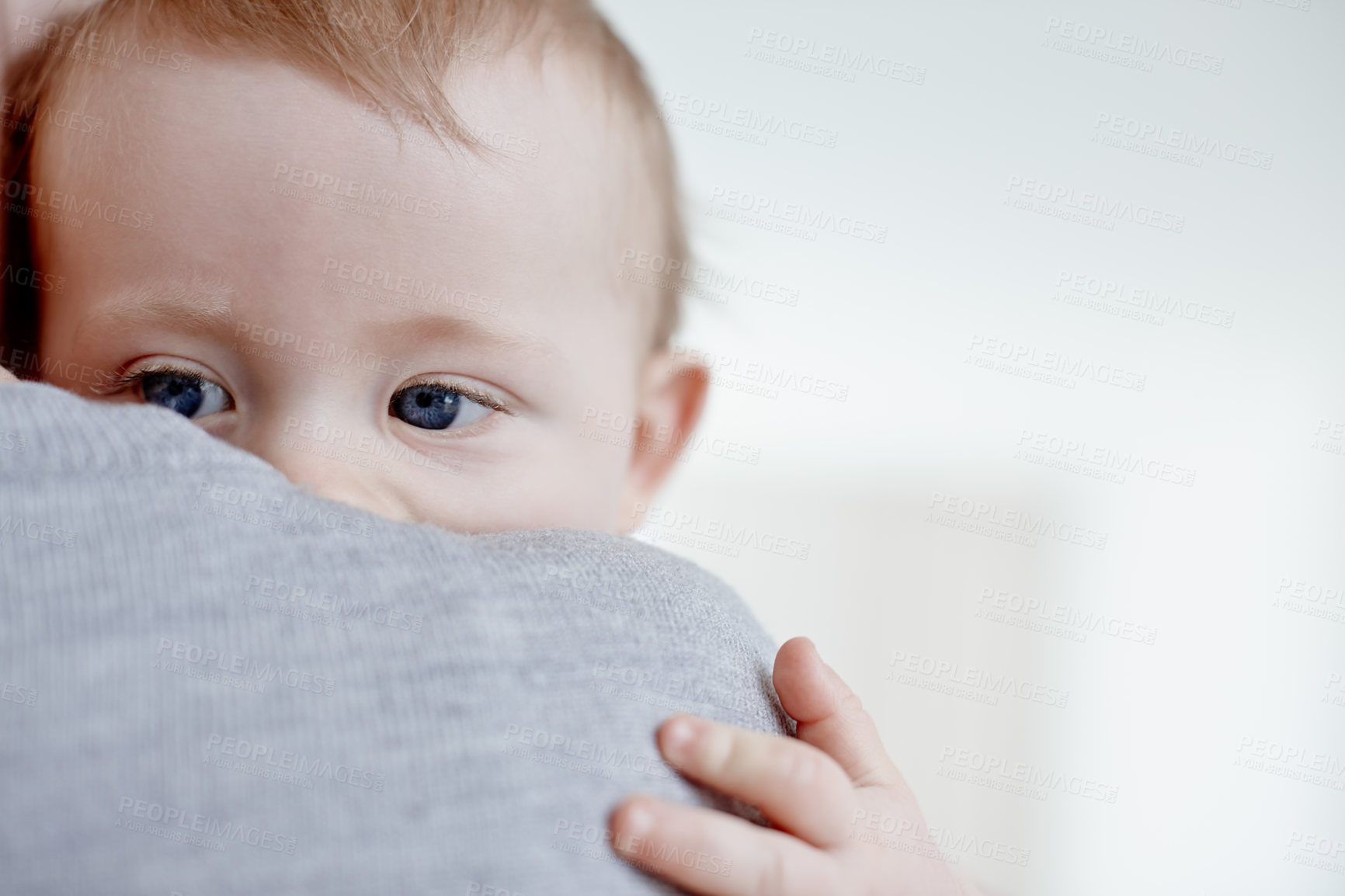 Buy stock photo Closeup of a cute baby boy holding on to his mother's shoulder