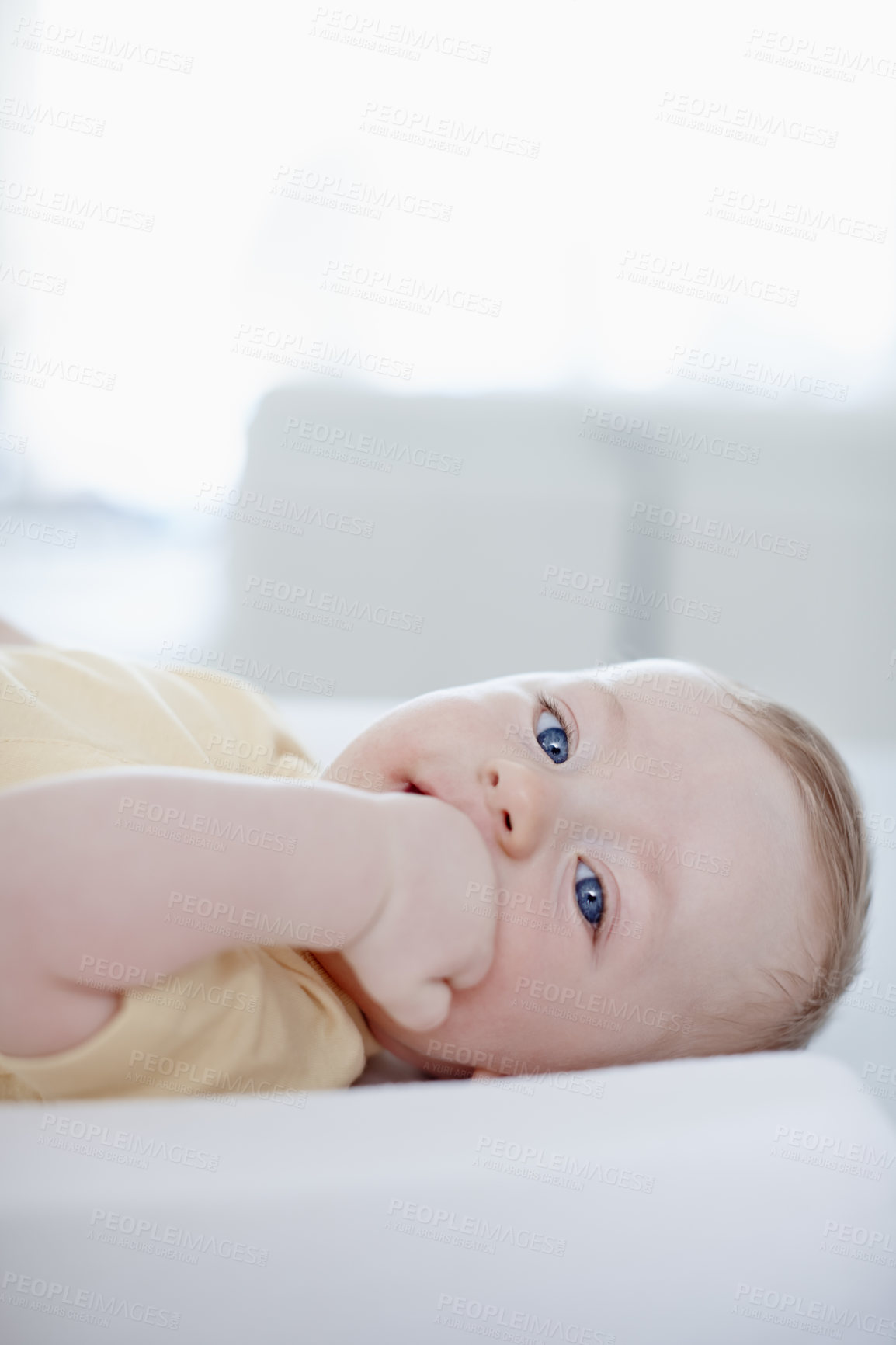 Buy stock photo A cute little baby boy lying on his back and looking at the camera