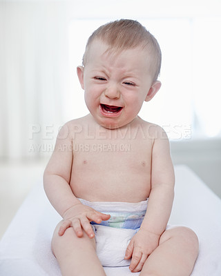 Buy stock photo A very unhappy baby boy sitting on a changing table