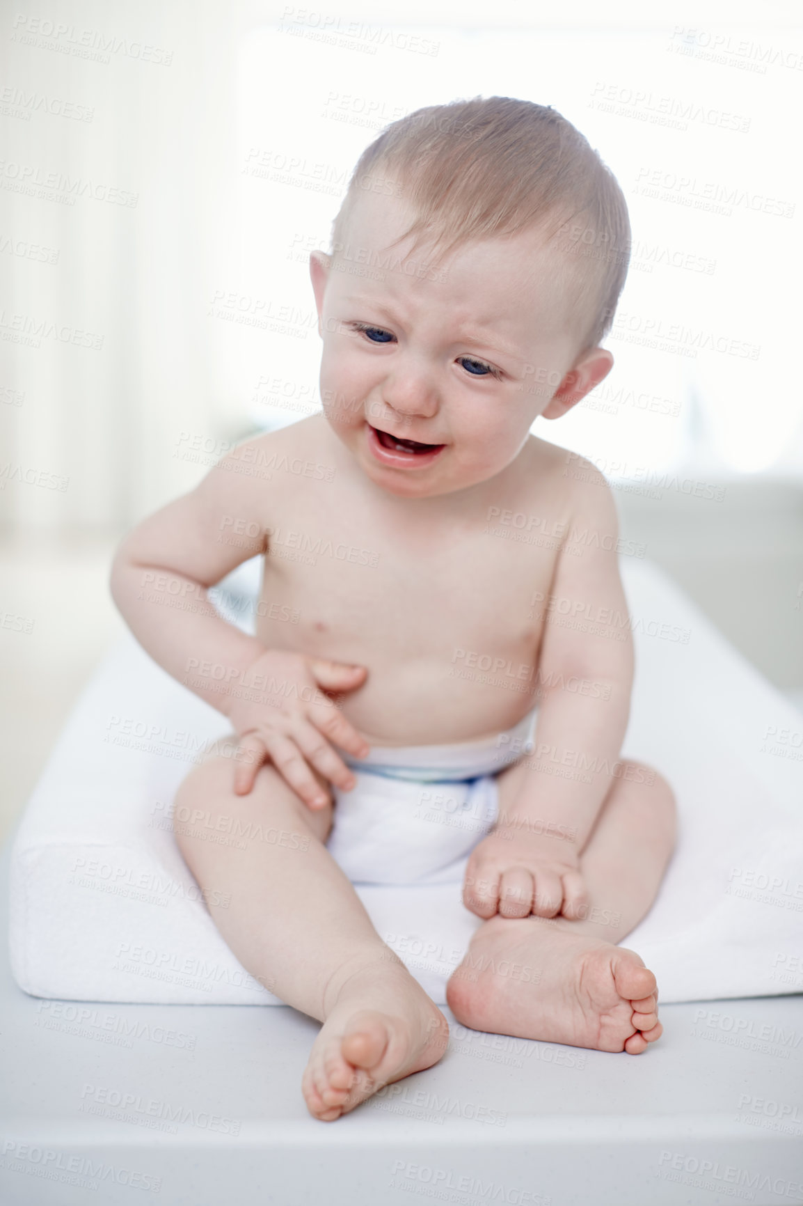 Buy stock photo A crying baby boy sitting on a changing table