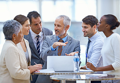 Buy stock photo Shot of a mature businessman explaining a concept to his colleagues in a meeting