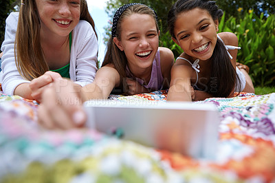 Buy stock photo Shot of a group of young girls taking a selfie together while lying on a blanket outside