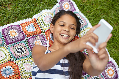 Buy stock photo Shot of a young girl taking a selfie while lying on a blanket in the outdoors