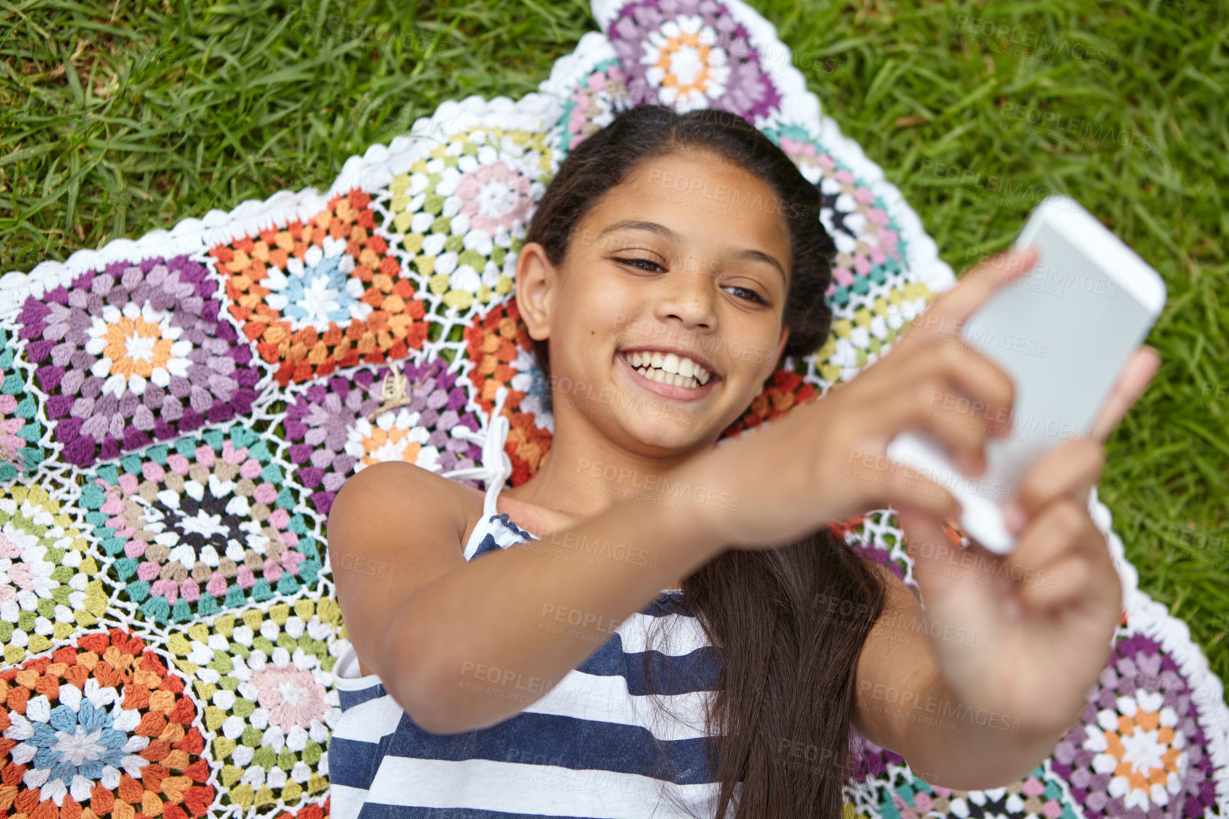 Buy stock photo Shot of a young girl taking a selfie while lying on a blanket in the outdoors