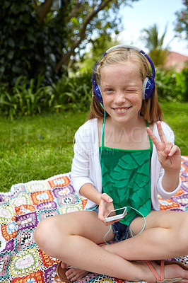 Buy stock photo Shot of a young girl listening to music on her cellphone while sitting outside