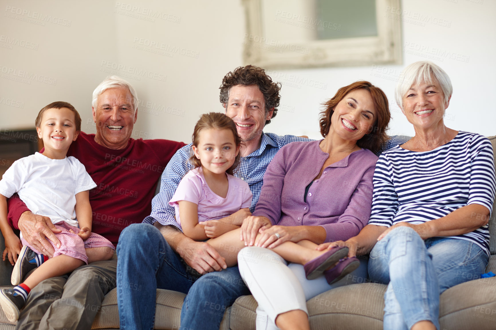 Buy stock photo Portrait of a happy multi-generational family sitting together on a sofa