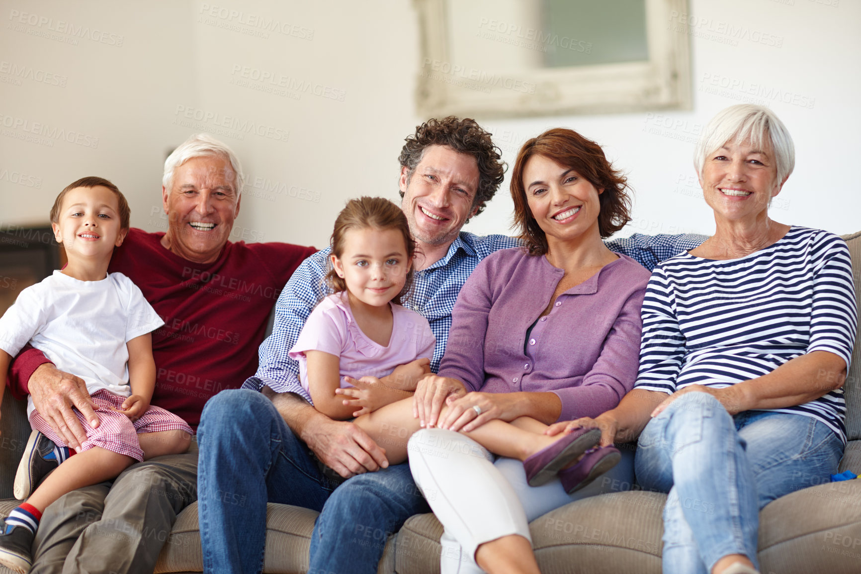 Buy stock photo Portrait of a happy multi-generational family sitting together on a sofa