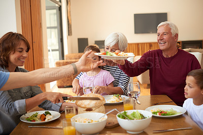 Buy stock photo Shot of a multi generational family having a meal together around a dining table