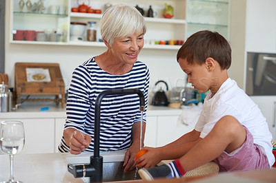 Buy stock photo Cropped shot of a grandmother washing vegetables with her grandchild in a kitchen