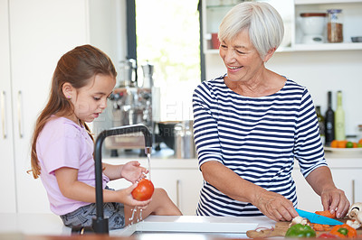 Buy stock photo Cropped shot of a grandmother washing vegetables with her grandchild in a kitchen
