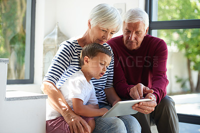 Buy stock photo Shot of a senior couple and their grandson using a digital tablet at home