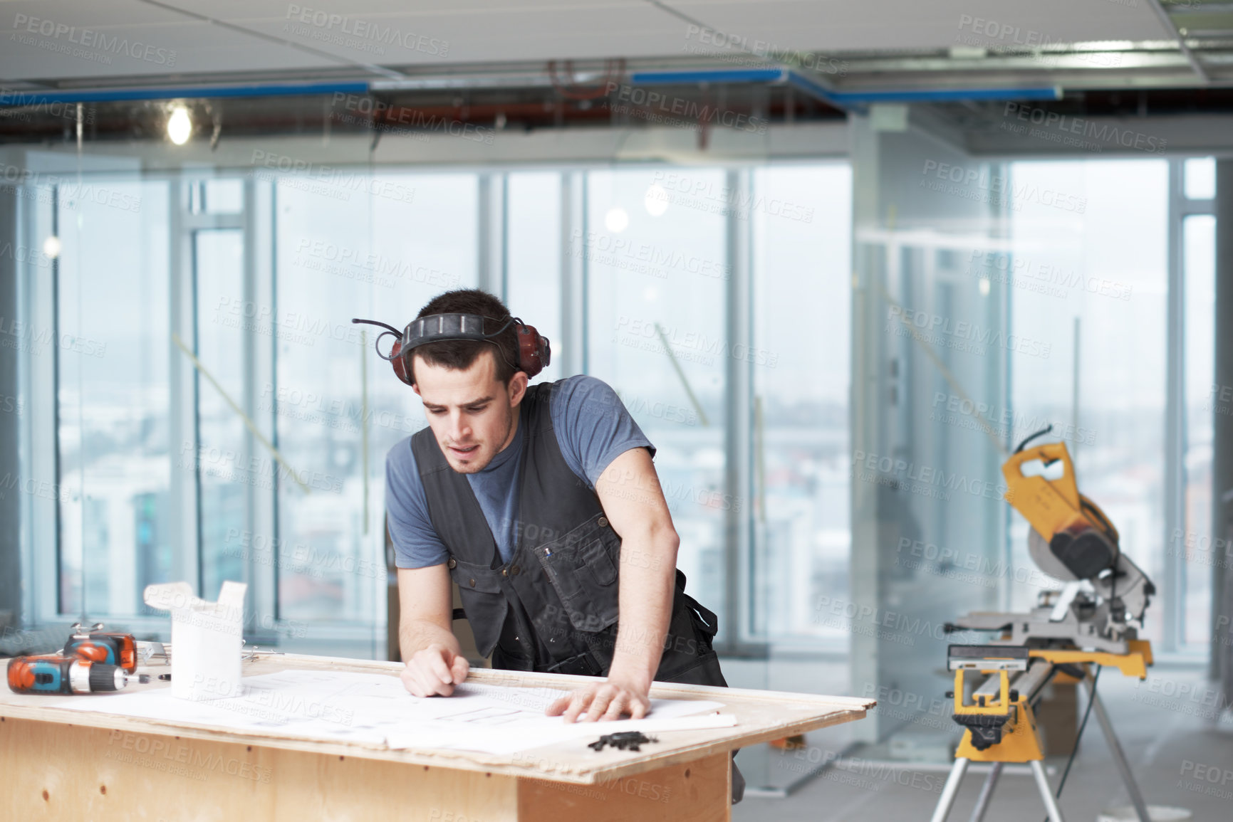 Buy stock photo Young architect working on his plans while at a construction site