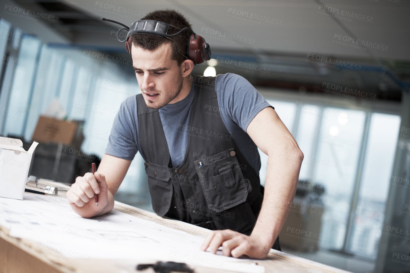 Buy stock photo Young architect working on his plans while at a construction site