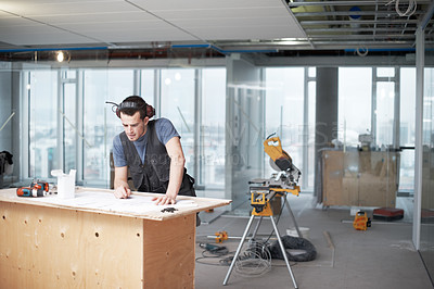 Buy stock photo Young architect working on his plans while at a construction site