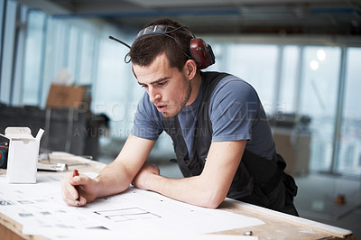 Buy stock photo Young architect working on his plans while at a construction site