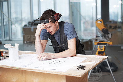 Buy stock photo Troubled architect working on his plans while at a construction site