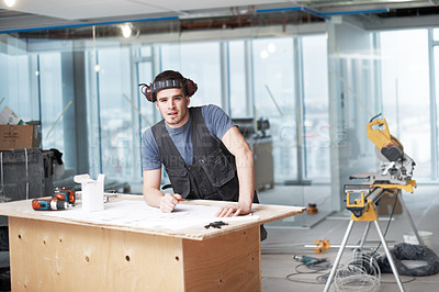 Buy stock photo Young architect working on his plans while at a construction site