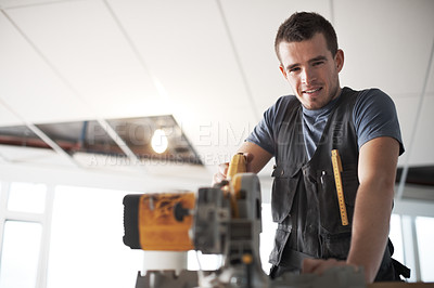 Buy stock photo Young contractor using a saw while on a construction site 