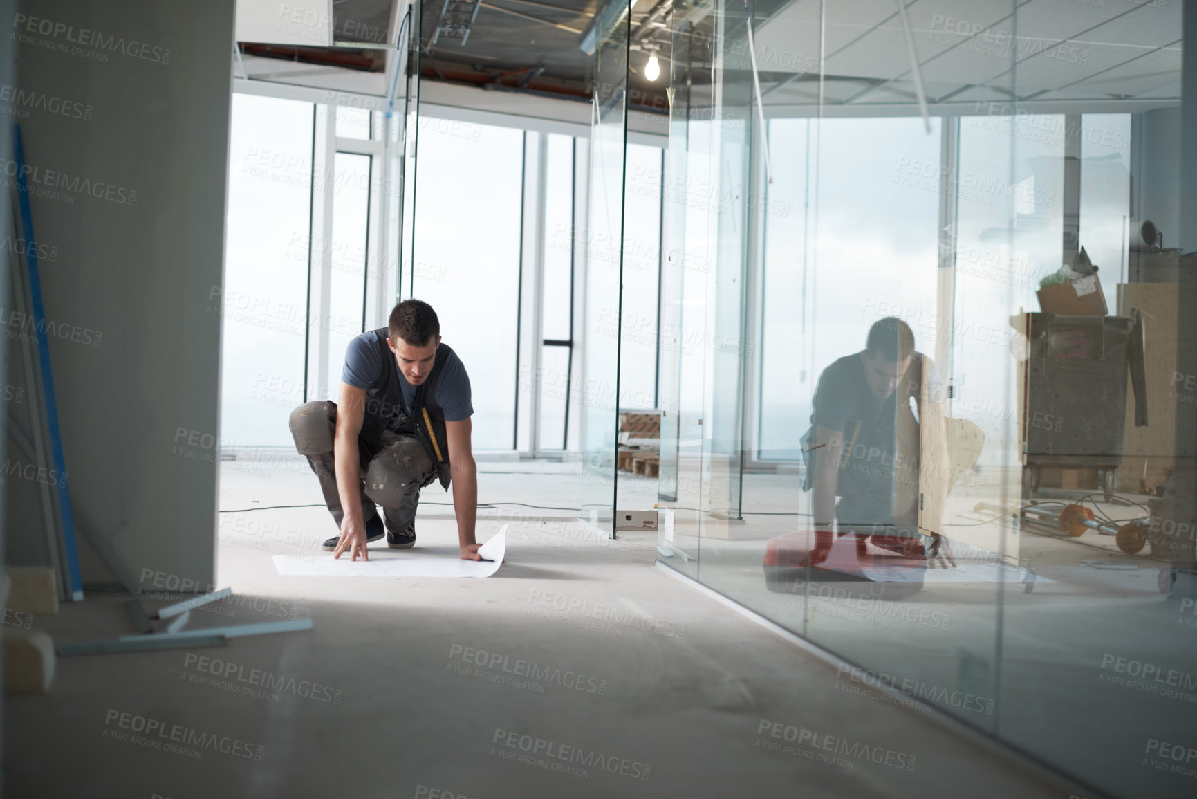 Buy stock photo Young contractor checking his plans on a construction site indoors