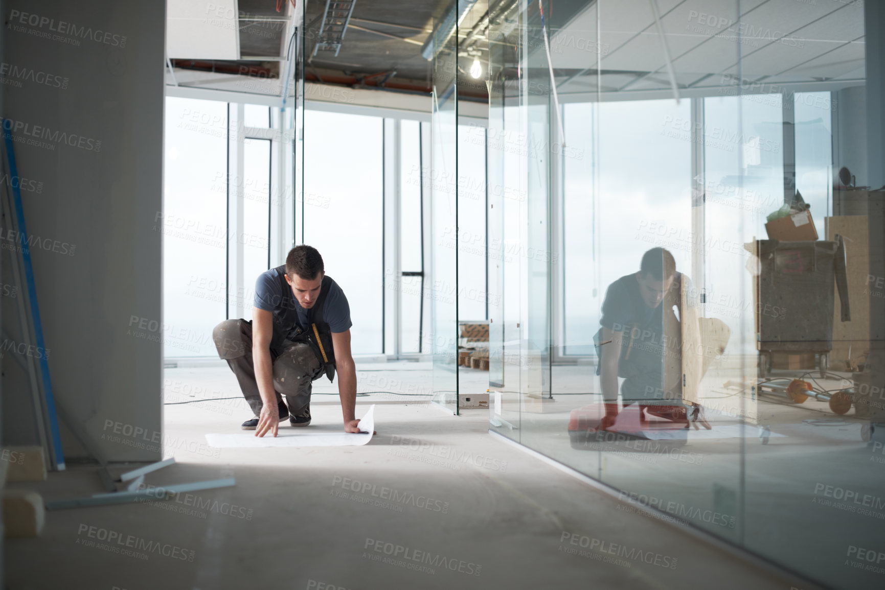 Buy stock photo Young contractor checking his plans on a construction site indoors