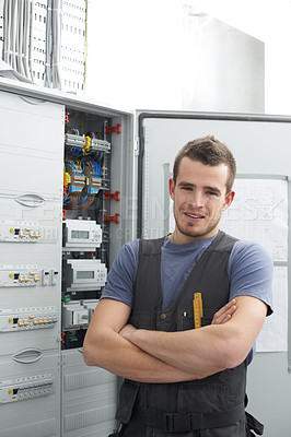 Buy stock photo Young contractor standing alongside an electrical distribution board