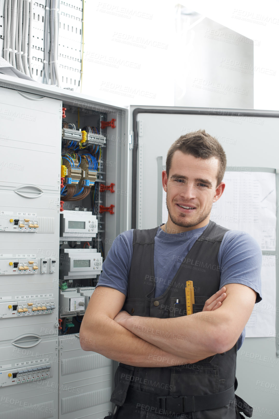 Buy stock photo Young contractor standing alongside an electrical distribution board