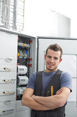 Buy stock photo Young contractor standing alongside an electrical distribution board