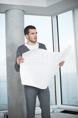 Buy stock photo Young architect checking his plans while standing in an empty room