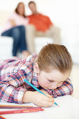 Buy stock photo A young girl lies on the floor and colours in