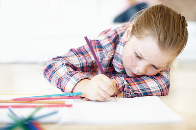 Buy stock photo A young girl lies on the floor and colours in 