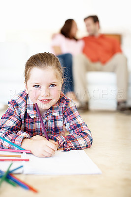 Buy stock photo A young girl colours in while her parents sit in the background