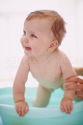 Buy stock photo A baby girl trying to get out of the bathtub while her mom holds her