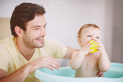 Buy stock photo A young father looking at his daughter with fondness while she's playing in the bath