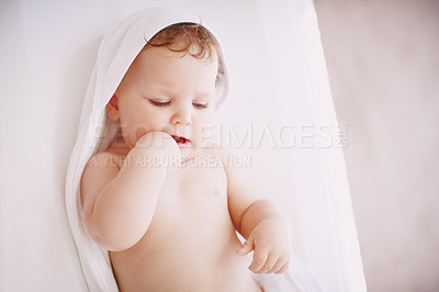 Buy stock photo A cute baby girl wrapped in a towel while lying down on a changing table