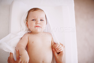 Buy stock photo A cute baby girl wrapped in a towel while lying down on a changing table