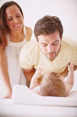 Buy stock photo A dad showing affection to his baby daughter as she lies on a changing table