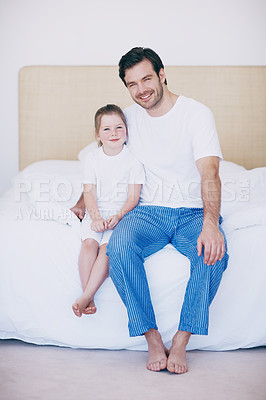 Buy stock photo Portrait of a dad and his young daughter sitting next to each other on a bed