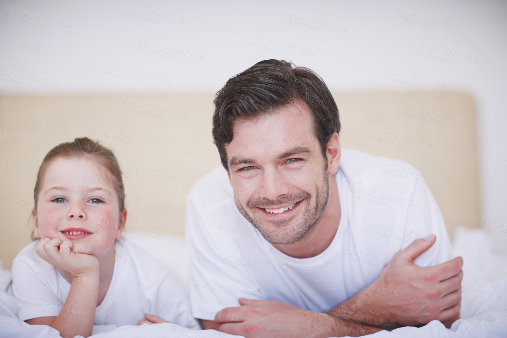 Buy stock photo A father and daughter lying side by side on a bed