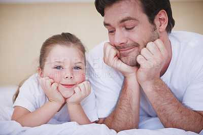 Buy stock photo A father and daughter lying side by side with their heads resting in their hands