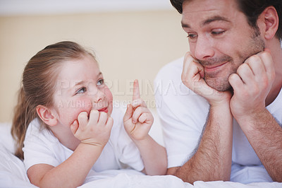 Buy stock photo Cropped shot of a father and daughter lying side by side on abed